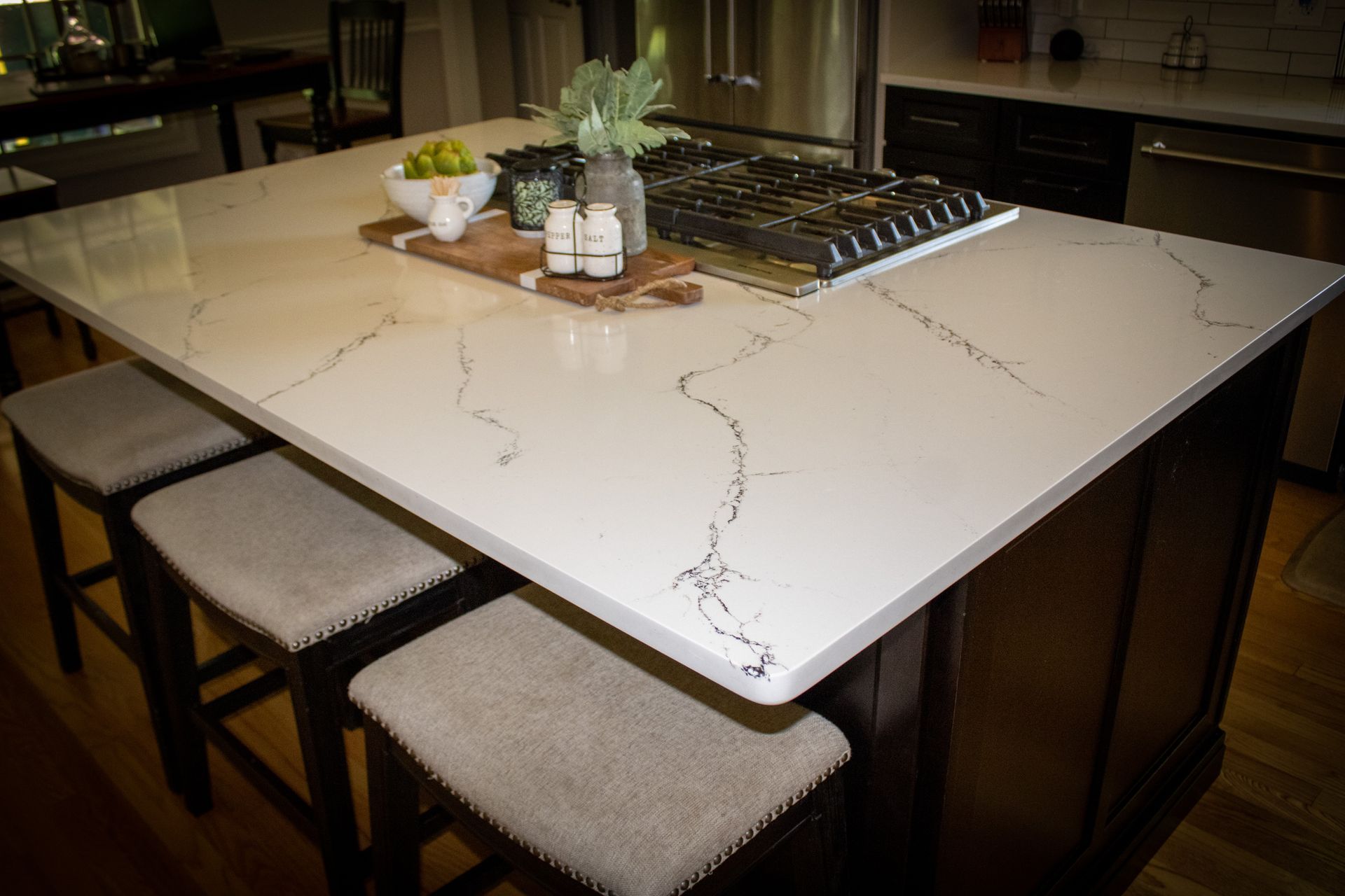 White quartz island with soft grey veining, a gas cooktop and dark cabinetry