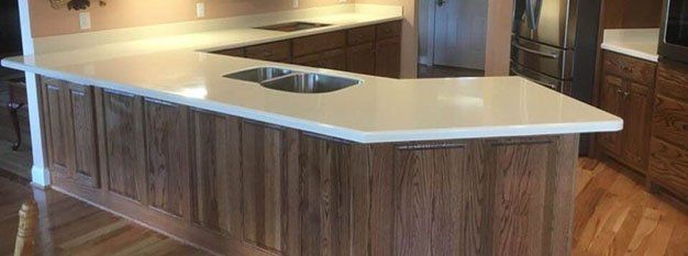 White solid surface peninsula with an integrated sink and oak cabinets